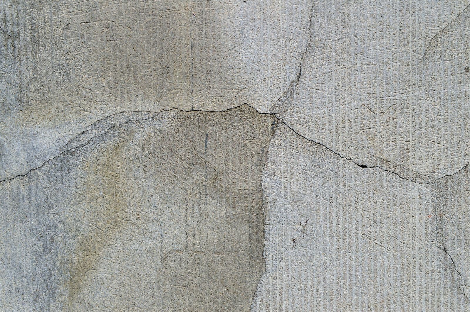 Sprunga liggur þvert yfir múrhúðaðan steinvegg utanhúss.